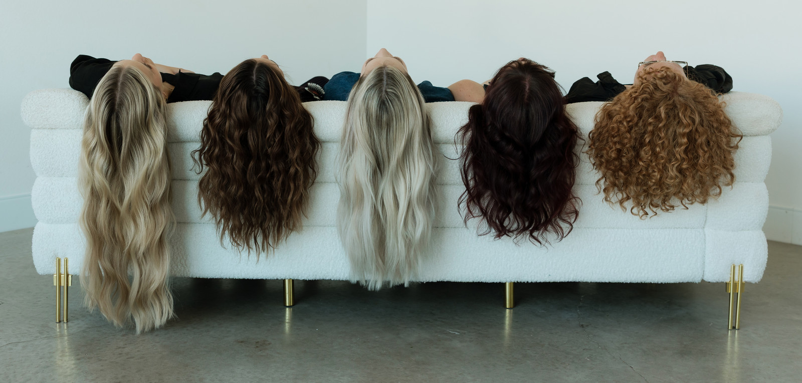 Five Socialite stylists lying on a white sofa with their hair hanging over the edge