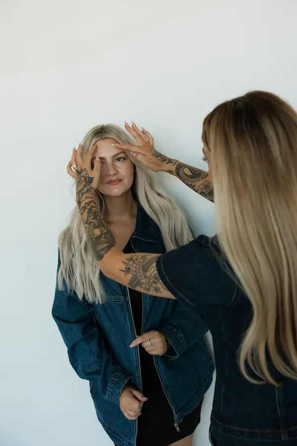 Stylist adjusting another stylist's long blonde hair