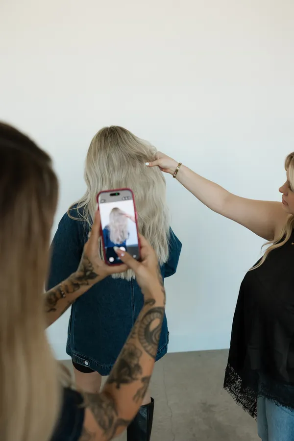 Stylist taking a phone photo of a finished blonde style