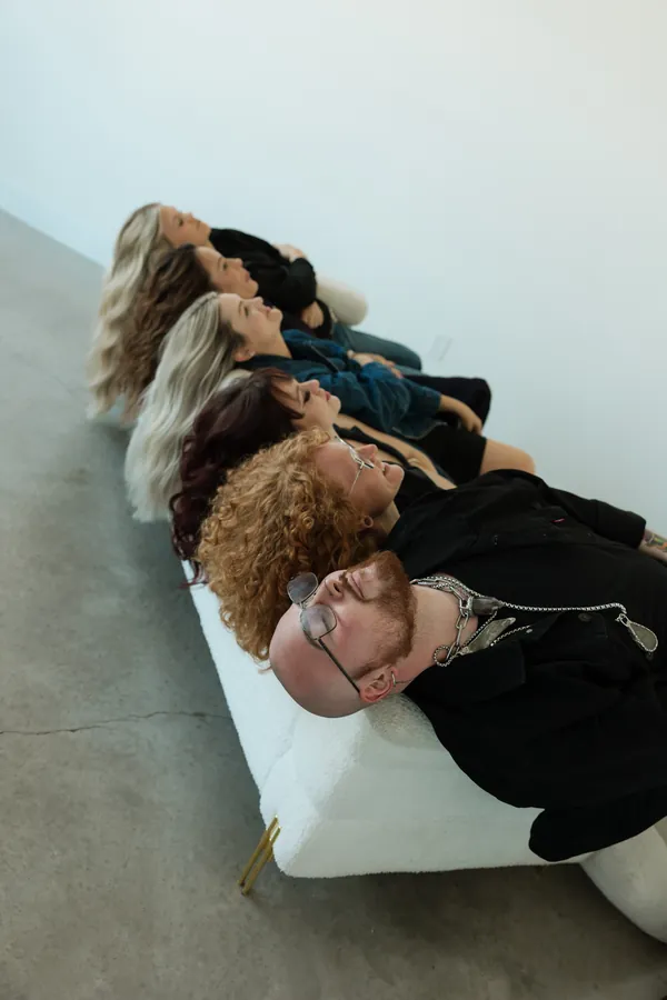 Stylists lying across a white sofa, showing off their hair